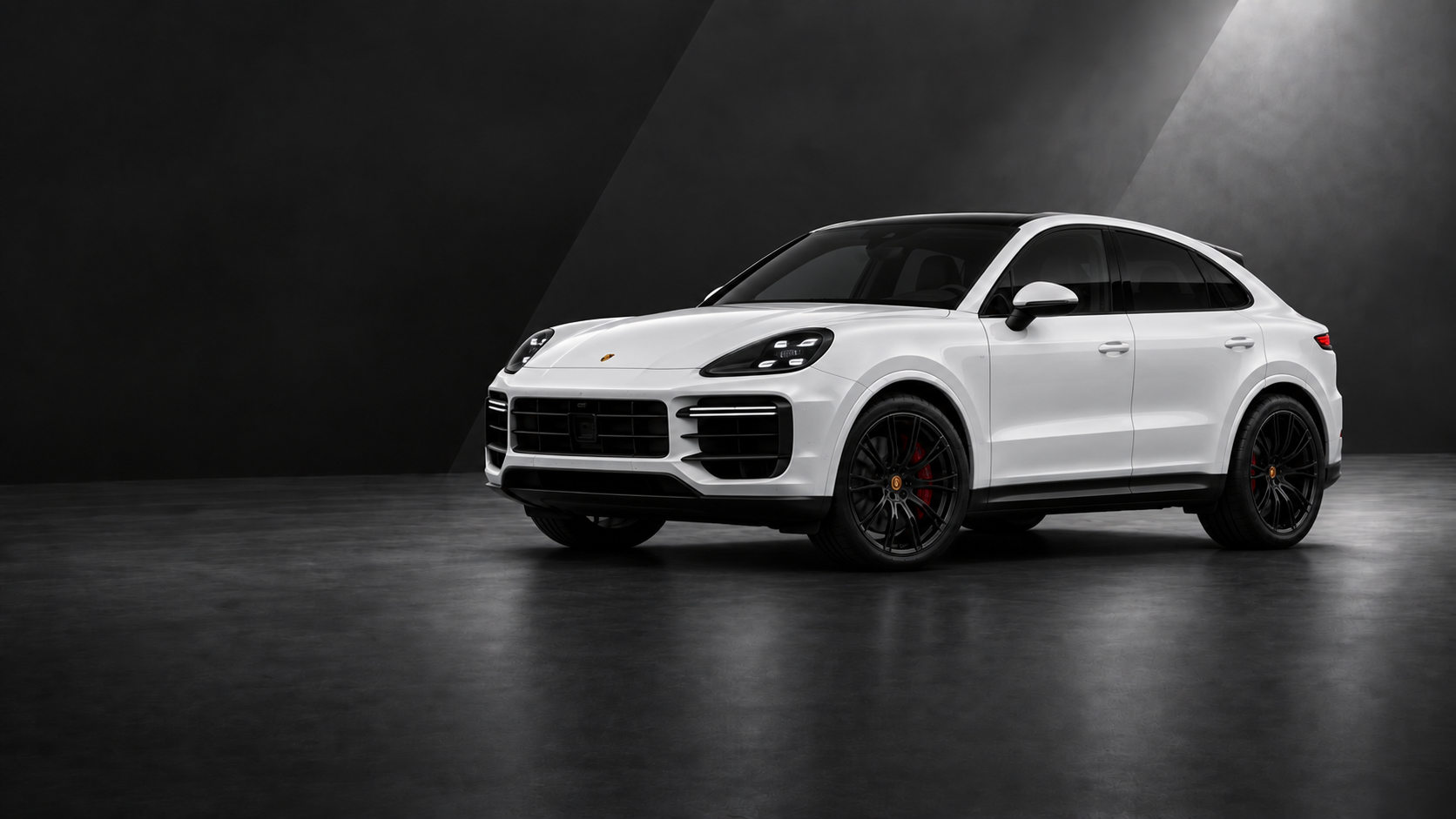 White Porsche Cayenne Coupe with tinted windows in a dark studio